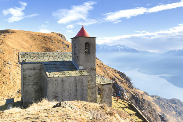 A boy looks the lake from the church of San Bernardo, Monte Bregagno, Dongo, Como Lake, Lombardy, Italy, Europe.