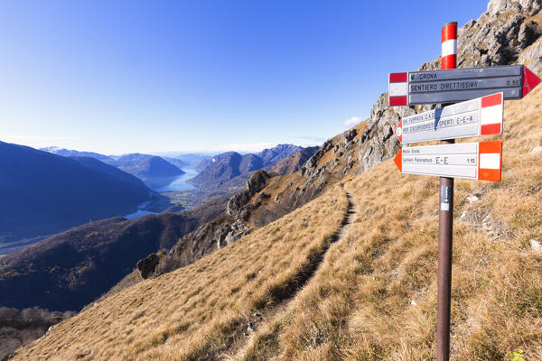 Signs along the ascent to Monte Grona with Lake of Lugano on the background. Monte Grona, Plesio, Como Lake, Lombardy, Italy, Europe