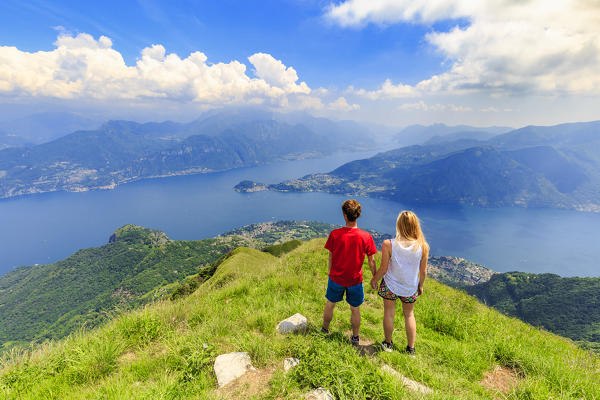 A couple of people looks Bellagio and Como Lake from  the top of Monte Crocione, Alpe Colonno, Pigra, Val d'Intelvi, Como Lake, Lombardy, Italy, Europe. (MR)