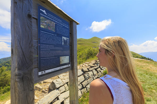 A girl reads an informative sign at the Alpe Colonno, Pigra, Val d'Intelvi, Como Lake, Lombardy, Italy, Europe.