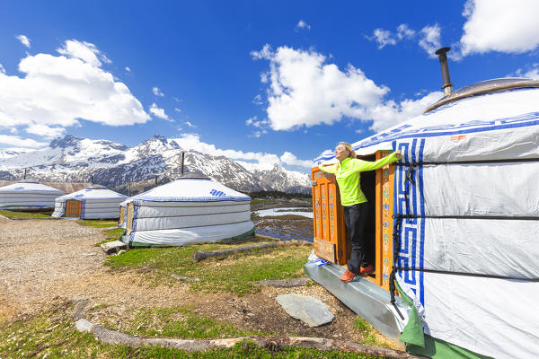 A girl stretches and breathes fresh air out of Mongolian tent. Alp Flix, Sur, Surses, Parc Ela, Region of Albula, Canton of Graubünden, Switzerland, Europe.