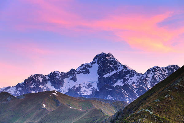 Colourful clouds above Mount Disgrazia during sunrise. Valtellina, Lombardy, Italy, Europe.