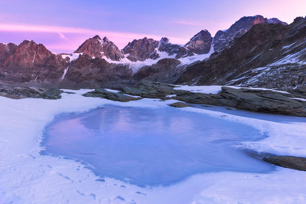 Frozen lake during sunrise on the Bernina mountain range. Bocchetta delle Forbici, Malenco Valley, Valtellina, Lombardy, Italy, Europe