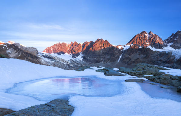 Frozen lake during sunrise on the Bernina mountain range. Bocchetta delle Forbici, Malenco Valley, Valtellina, Lombardy, Italy, Europe