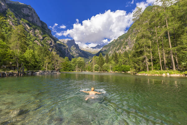 A girl swims in a clear alpine lake. Val di Mello(Mello Valley), Valmasino, Valtellina, Lombardy, Italy, Europe.