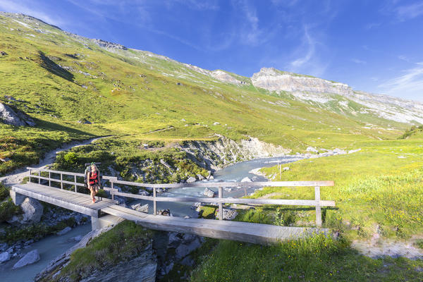 Hiker girl run across a pedestrian bridge. Unterer Segnesboden, Flims, District of Imboden, Canton of Grisons, Switzerland, Europe