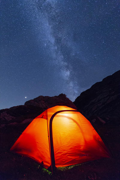 Milky way above a illuminated tent. Unterer Segnesboden, Flims, District of Imboden, Canton of Grisons, Switzerland, Europe