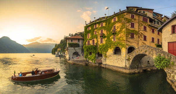 A boat of tourists stops to observe the sunset. Nesso, Province of Como,  Como Lake, Lombardy, Italy, Europe.