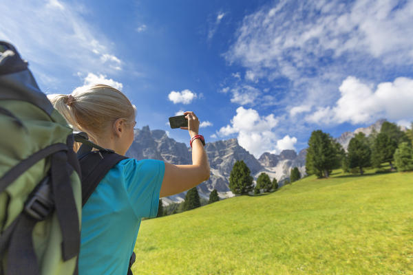 Girl take a photo with a smartphone. Longiarù, Badia Valley, South Tyrol, Dolomites, Italy, Europe. (MR)