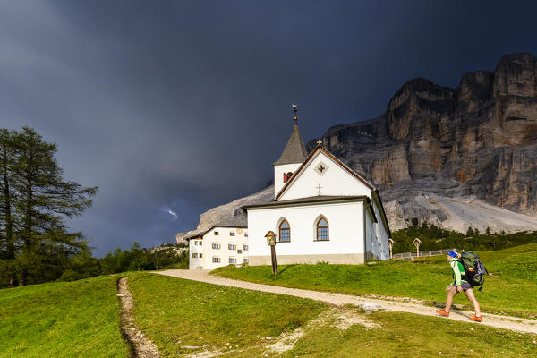 Hiker walk on a path near Santa Croce Sanctuary with coming thunderstorm. La Valle/La Val/Wengen Badia Valley, South Tyrol, Dolomites, Italy, Europe. (MR)