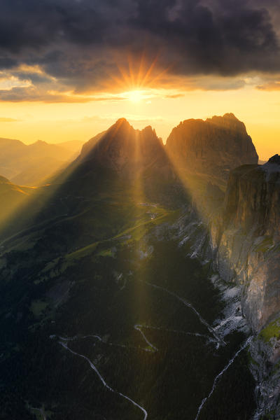 Sun rays filters between stormy clouds during sunset with Sassolungo group in the foreground. Fassa Valley, Trentino, Dolomites, Italy, Europe.