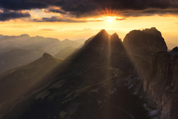 Sun rays filters between stormy clouds during sunset with Sassolungo group in the foreground. Fassa Valley, Trentino, Dolomites, Italy, Europe.