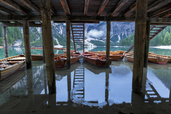 Boats moored under the stilt house. Braies Lake / Pragser Wildsee,  Braies / Prags, Dolomites, South Tyrol, Italy,  Europe.