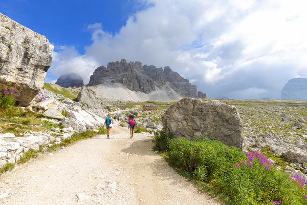 Two hikers walk pathway for Lavaredo Refuge. Dolomites of Sesto / Sexten, Province of Belluno, Veneto, Italy,  Europe.