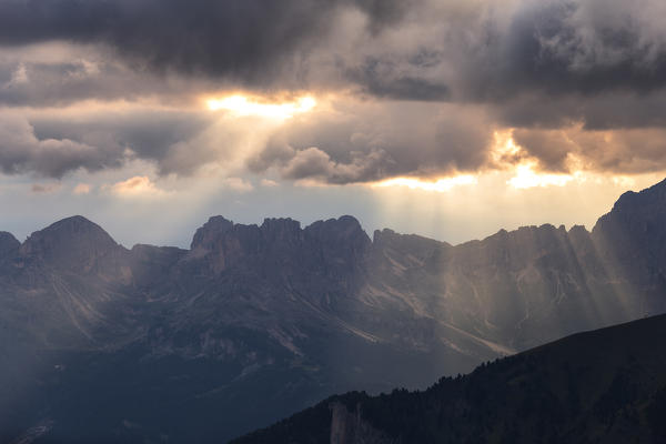 Light filters between black clouds. San Nicolò Pass, Fassa Valley, Trentino, Dolomites, Italy, Europe.