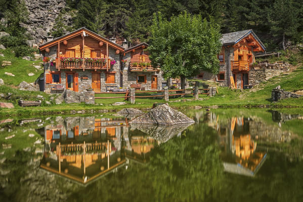 Huts of Lagunc village reflected into a pond, San Giacomo Filippo, Sondrio province, Chiavenna valley, Lombardy, Italy, Europe