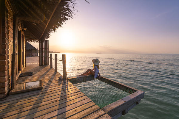 Azul Paradise resort, Bastimentos island, Bocas del Toro province, Panama, Central America. A young woman admires the sunrise on a overwater bungalow.  (MR) (PR)