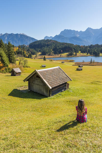 Gerold, Garmisch Partenkirchen, Bavaria, Germany, Europe. Young woman relaxing on a meadow near lake Geroldsee, Karwendel range in the background