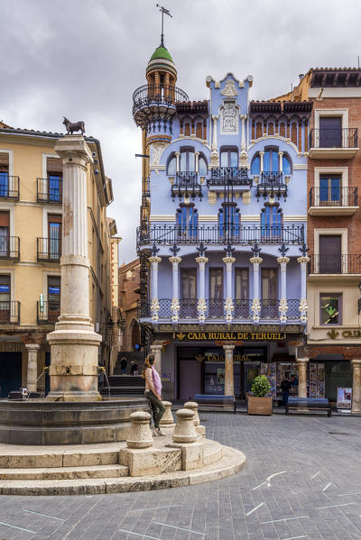 A tourist is sitting on the fountain in Plaza del Torico, Teruel, Aragon, Spain, Europe