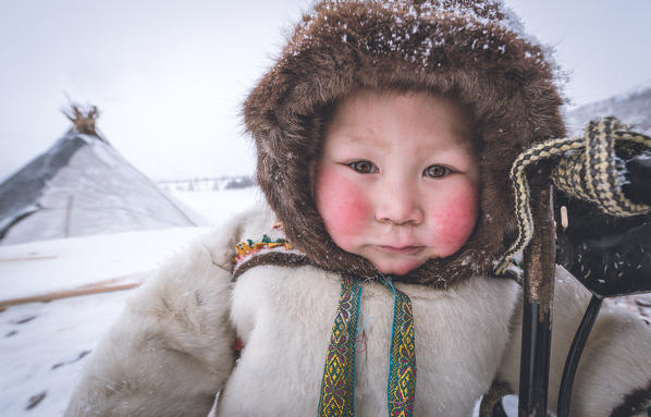 A young nenets boy dressed with the traditional coat. Daily life at the nomadic reindeer herders camp. Polar Urals, Yamalo-Nenets autonomous okrug, Siberia, Russia