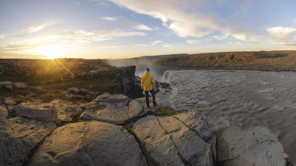 a person enjoys the sunset near a Dettifoss waterfall, during a sunset with a midnight sun, Nordurland, Iceland, Europe