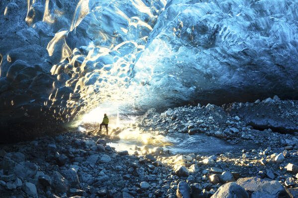 one hiker admiring one ice cave in Jokusarlon Glacier Lagoon area in winter time, Austurland, Iceland, Europe