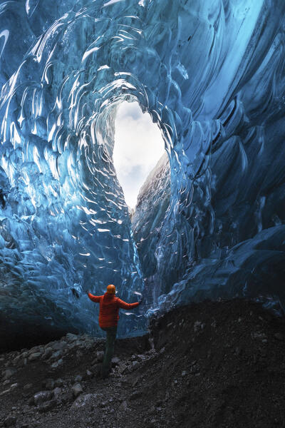 one hiker admiring one ice cave in Jokusarlon Glacier Lagoon area in winter time, Austurland, Iceland, Europe