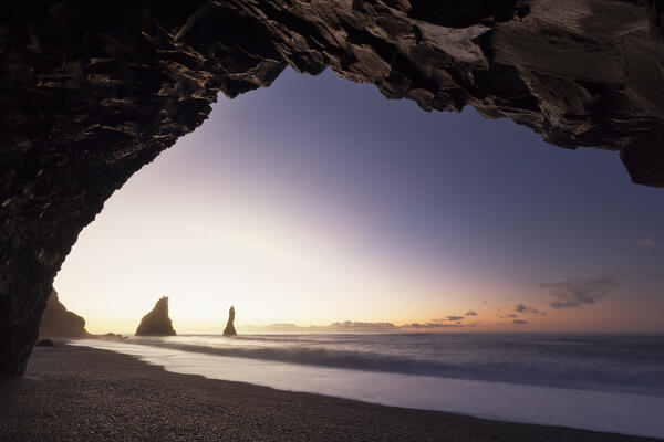 the stacks of Vik i Myrdal, seen from an sea cave during a winter sunrise, Reynisfjara beach, southern Iceland, Europe