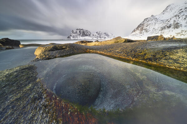 a long exposure to capture the sunset light at Uttakleiv beach during an winter day, with a famous eye of dragon in foreground, Vestvagoy, Lofoten island, Norway, Europe