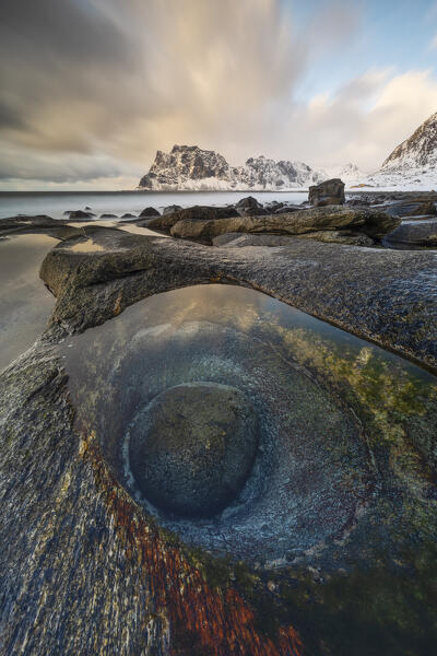 a long exposure to capture the sunset light at Uttakleiv beach during an winter day, with a famous eye of dragon in foreground, Vestvagoy, Lofoten island, Norway, Europe