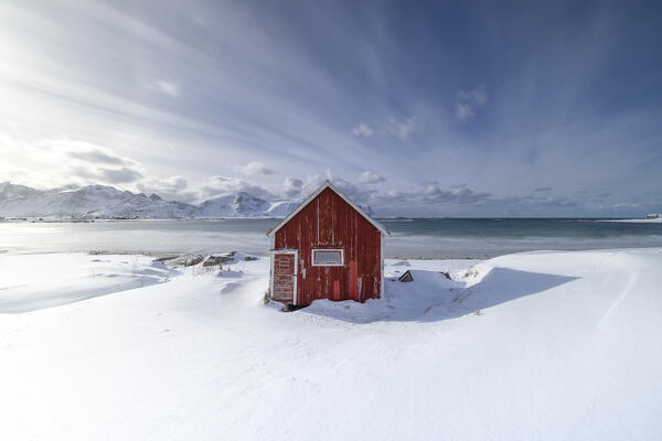 a long exposure to capture the afternoon light at Ramberg beach, with an classic Rorbuer in to the snow, Ramberg, Lofoten island, Norway, Europe
