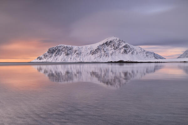 a warm light envelope the iconic mountainn in front at Skagsanden beach during a winter sunset, Ramberg, Lofoten island, Norway, Europe
