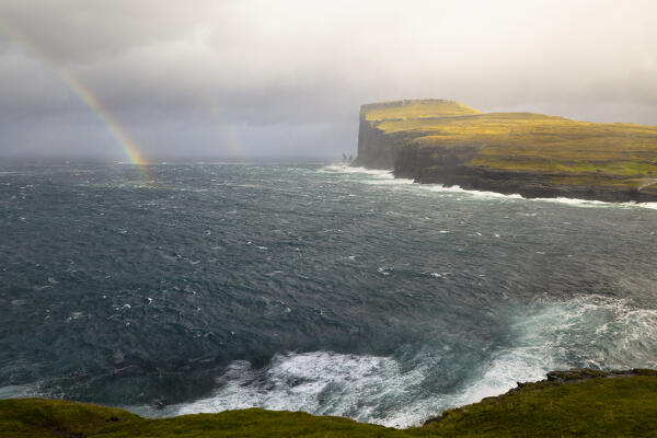 one sea storm hits the Risin og Kellingin cliffs during an autumn day with a rainbow in the sea, Eysturoy, Faroe Islands, Denmark, Scandinavia