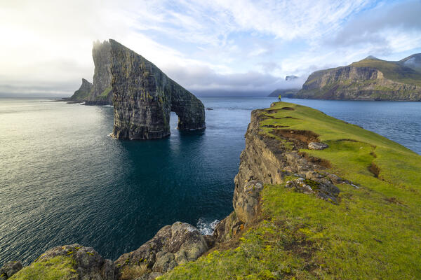 A tourist observes Drangarnir during an autumn day, Vagar, Faroe Islands, Denmark, Scandinavia, Europe