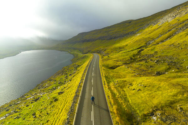 one people enjoy the beautiful light in the middle of the road, along the Funningsfjordur, Eysturoy, Faroe Island, Denmark, Europe