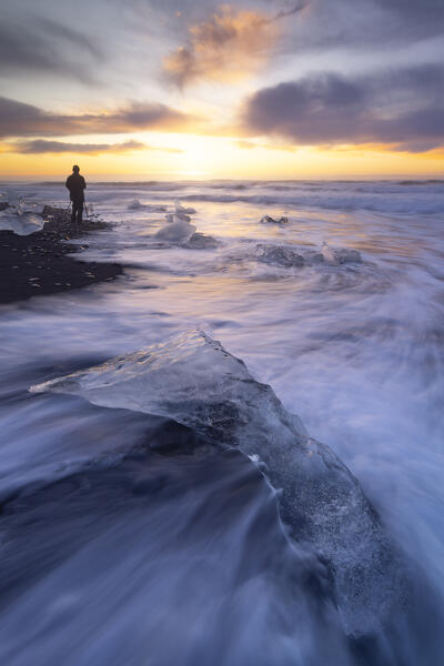 the ice blocks of the famous Black Sand Beach with a photographer in foreground, taken during an autumn sunrise, Jokusarloon, Iceland, Europe