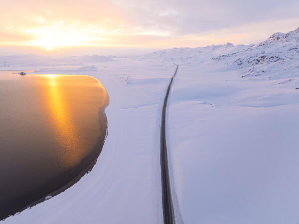 an aerial view taken by drone of the road that runs along Lake Kleifarvatn, during a magnificent winter sunset, Iceland, Europe