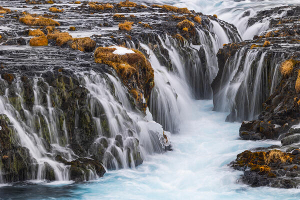 the incredibly colorful details of the famous Bruarfoss waterfall, with its turquoise water and golden grass, taken on a cold winter day, Iceland, Europe