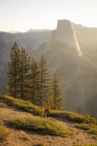 a man watches the sunrise in front of the iconic Half Dome mountain, Yosemite National Park, California, United States of America