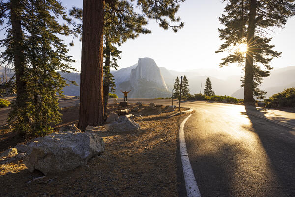 a man watches the sunrise in front of the iconic Half Dome mountain, Yosemite National Park, California, United States of America