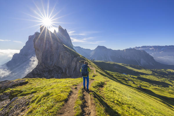 A man walks at Seceda during sunrise, Gruppo delle Odle, Dolomiti di Gardena, Bolzano, Trentino Alto Adige, Italy, Southern Europe (MR)