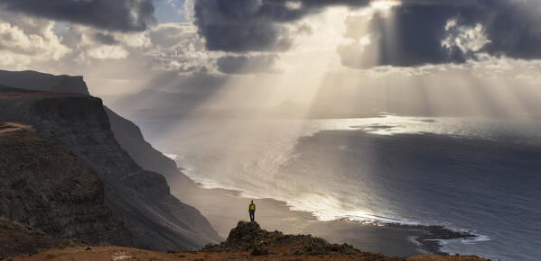 Panoramic view of a man observes Atlantic Ocean from Famara promontory at sunset, Famara, Las Palmas, Lanzarote, Canary Islands, Macaronesia, Spain, Western Europe (MR)