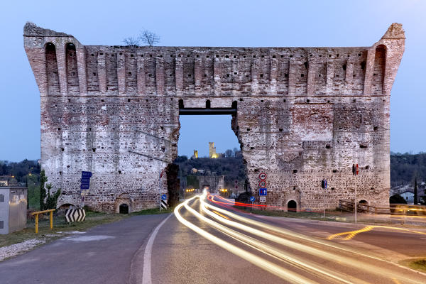 Traffic trails at the entrance to the Visconti bridge. In the background the Scaligero castle of Valeggio sul Mincio. Verona province, Veneto, Italy, Europe.