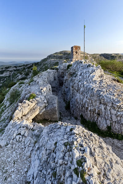 Mount Ortigara: Austro-Hungarian Great War trenches carved into the rock and the memorial stone. Asiago plateau, Vicenza province, Veneto, Italy, Europe.