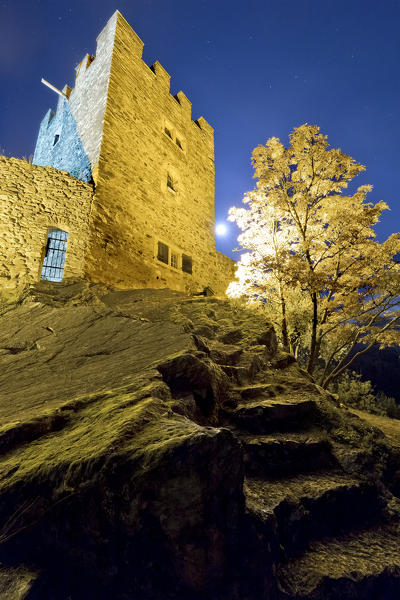 Steps carved into the rock and the quadrangular tower of the castle of Pergine on a full moon night. Trento province, Trentino Alto-Adige, Italy, Europe.