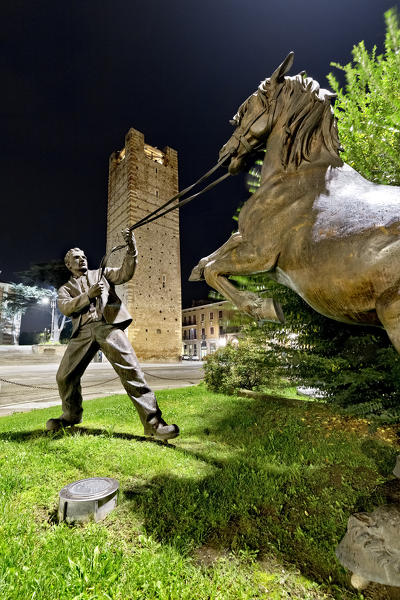 The sculpture of the Lonigo horse fair. In the background the Scaliger tower. Vicenza province, Veneto, Italy, Europe.