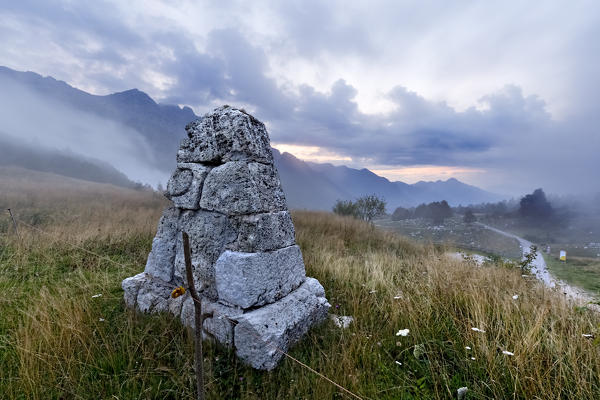 Boundary stone of 1751 between the Republic of Venice and the Austrian Empire. In the background the mounts Carega and Zugna. Piccole Dolomiti, Vicenza province, Veneto, Italy, Europe.