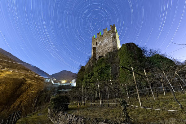 Star trails above the Segonzano Castle: ancient legends haunt these medieval ruins. Cembra valley, Trento province, Trentino Alto-Adige, Italy, Europe.