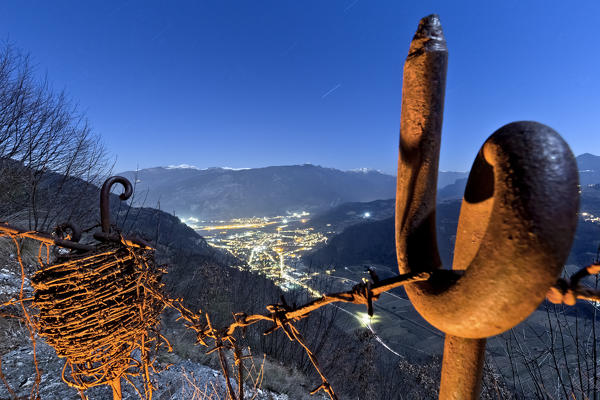 Barbed wire of the Great War stronghold on Mount Nagià-Grom. In the background the Lagarina valley and the Mount Zugna. Gresta valley, Trento province, Trentino Alto-Adige, Italy, Europe. 
