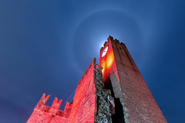 Lunar halo over the clock tower of the Scaliger castle of Villafranca di Verona. Verona province, Veneto, Europe, Italy.